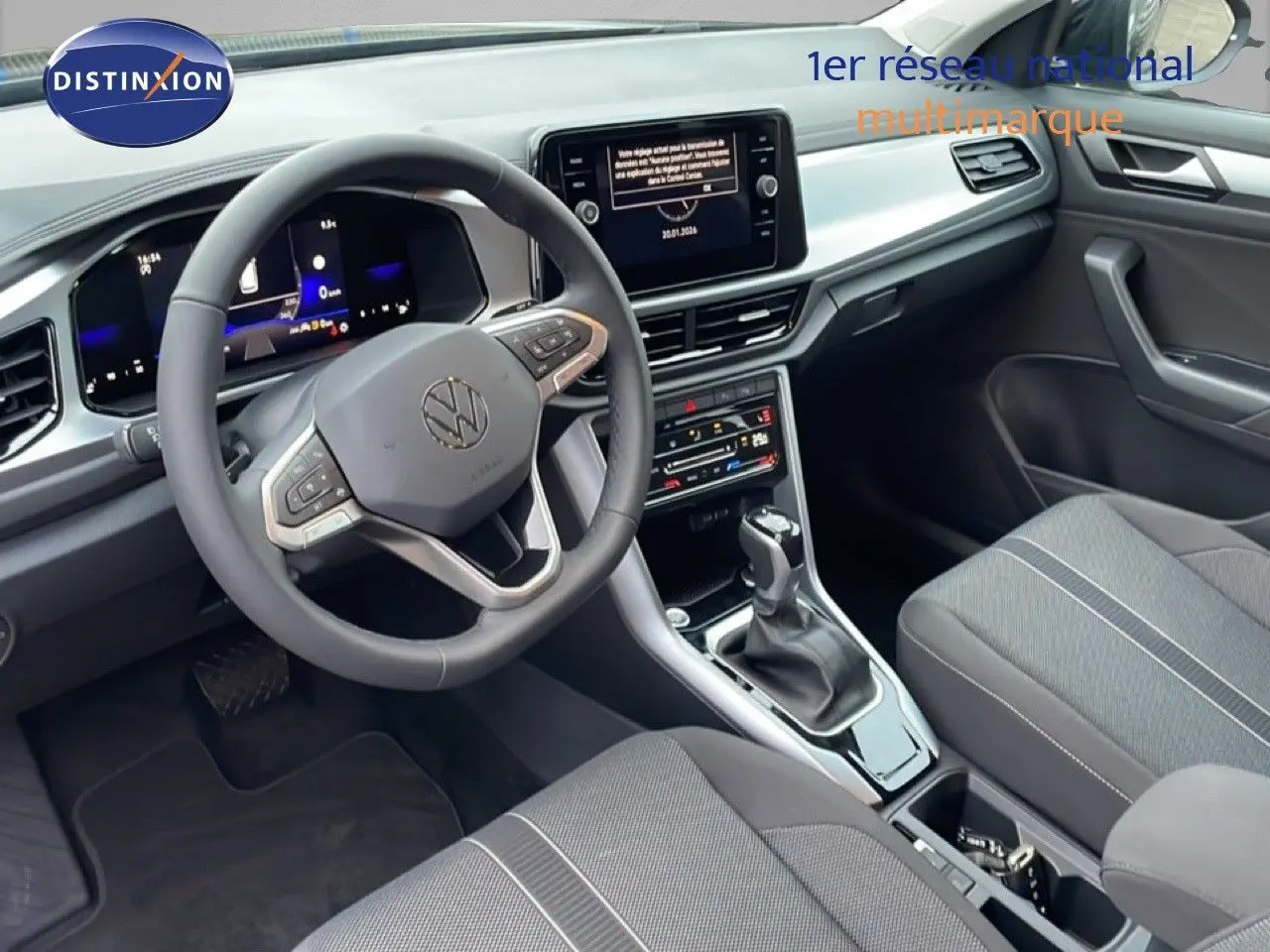 Vue intérieure côté conducteur du Volkswagen T-Roc 1.5 TSI noir, mettant en valeur le volant multifonction et l'écran central tactile.