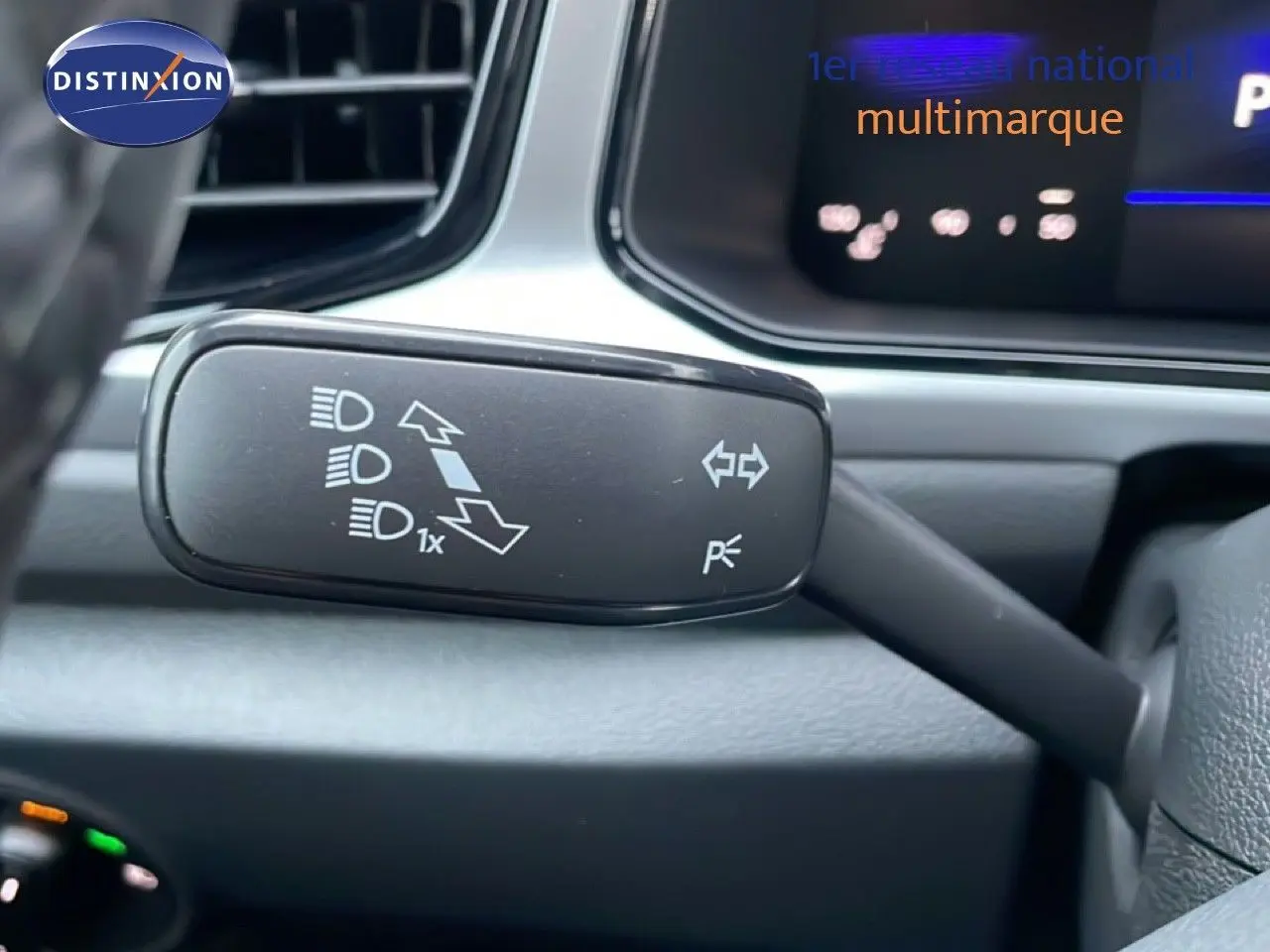 Gros plan sur la commande de clignotant et feux d’un Volkswagen T-Roc noir Grenadilla, intérieur moderne et tableau de bord partiel.