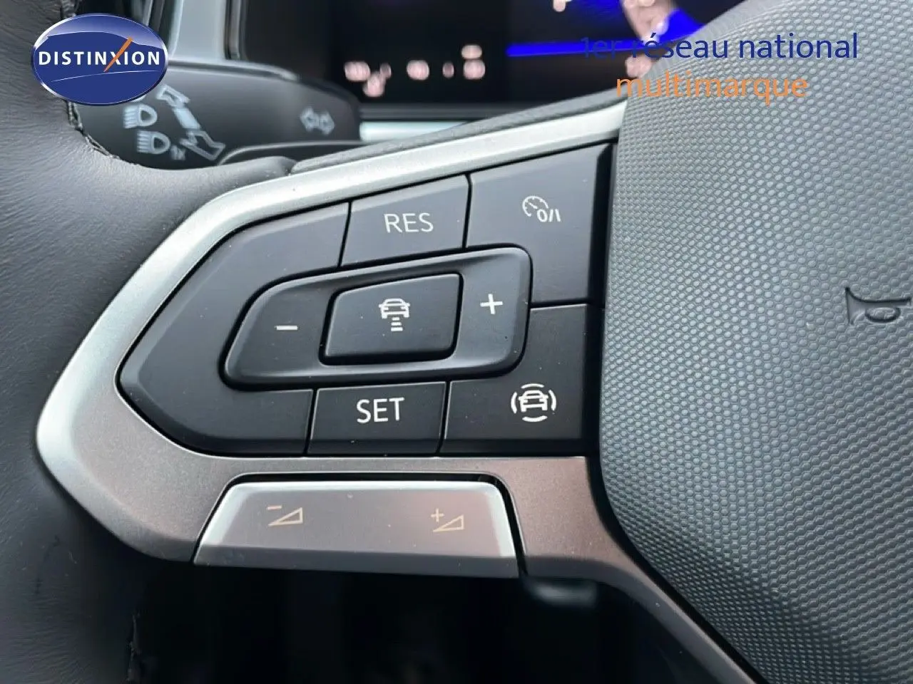 Gros plan sur les commandes au volant du Volkswagen T-Roc 1.5 TSI noir Grenadilla, mettant en valeur les boutons de régulateur de vitesse.