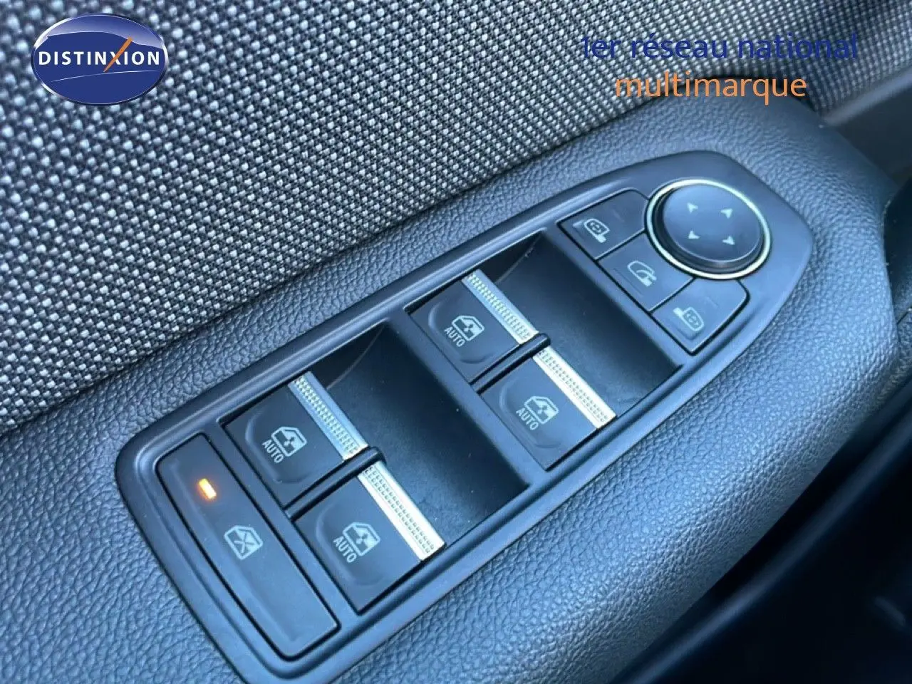 Gros plan sur les commandes des vitres électriques côté gauche du Renault Captur 2025 rouge désir métal avec toit noir.