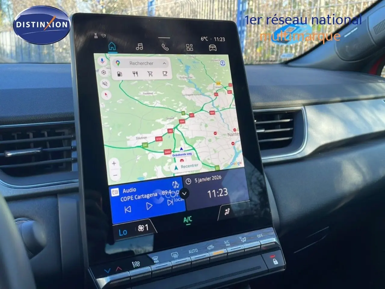 Vue rapprochée de l’écran tactile central du Renault Captur rouge désir métal avec toit noir, affichant la navigation GPS et la climatisation.