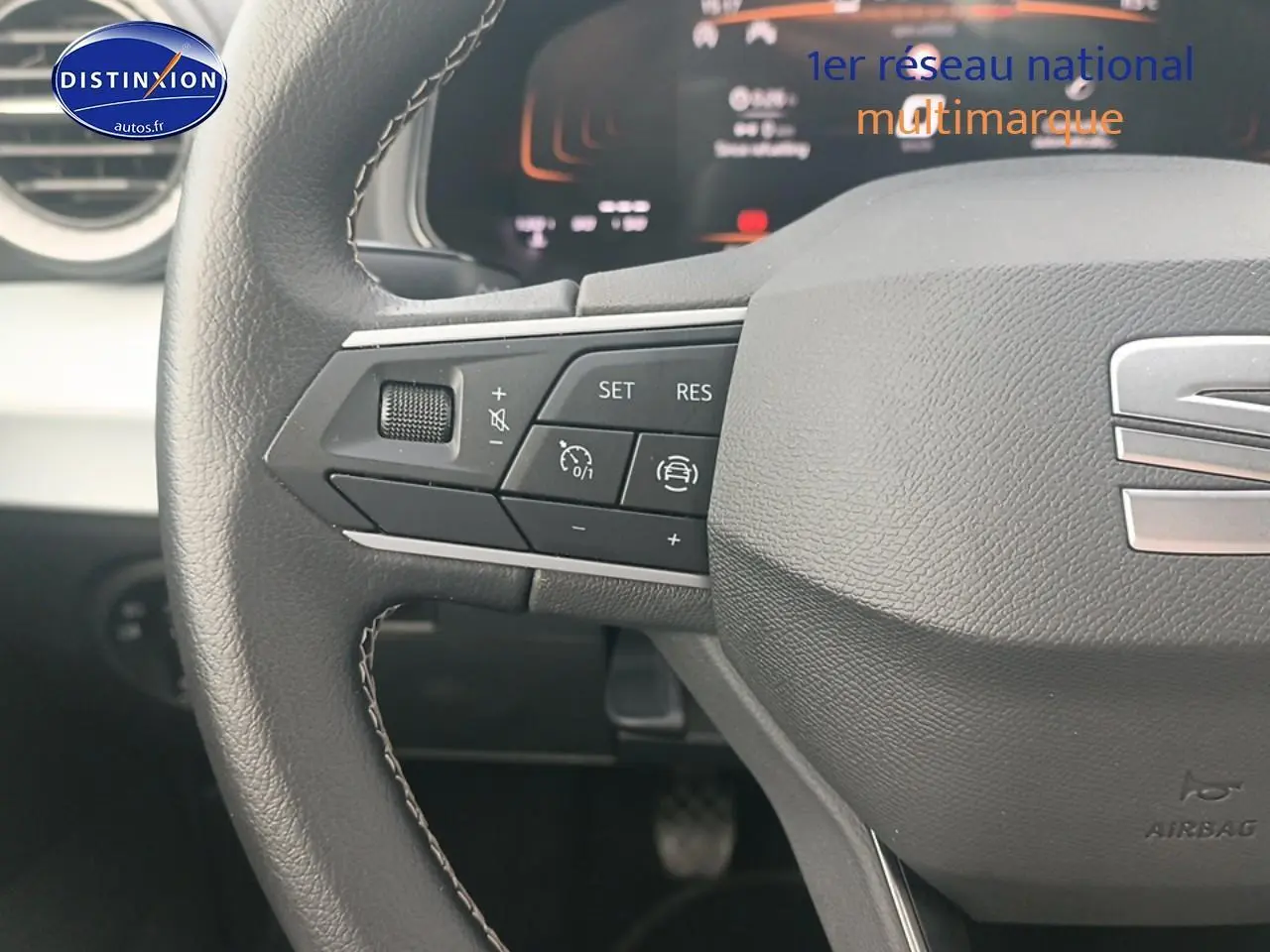 Gros plan sur le volant cuir noir multifonction avec logo SEAT et commandes de régulateur de vitesse.
