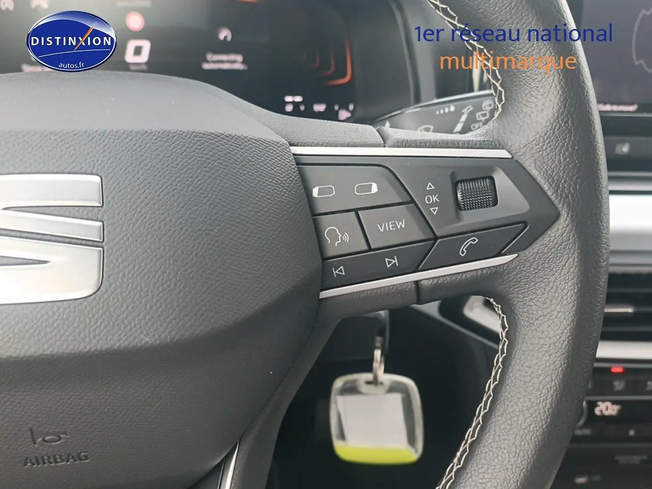 Gros plan sur le volant cuir noir de la SEAT Ibiza blanc Nevada, avec commandes multifonctions et logo satiné visible.
