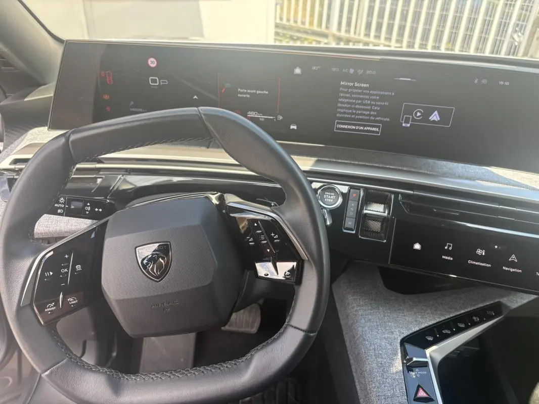 Vue intérieure du tableau de bord du Peugeot 3008 Hybrid 2025, avec volant compact et écran tactile panoramique.