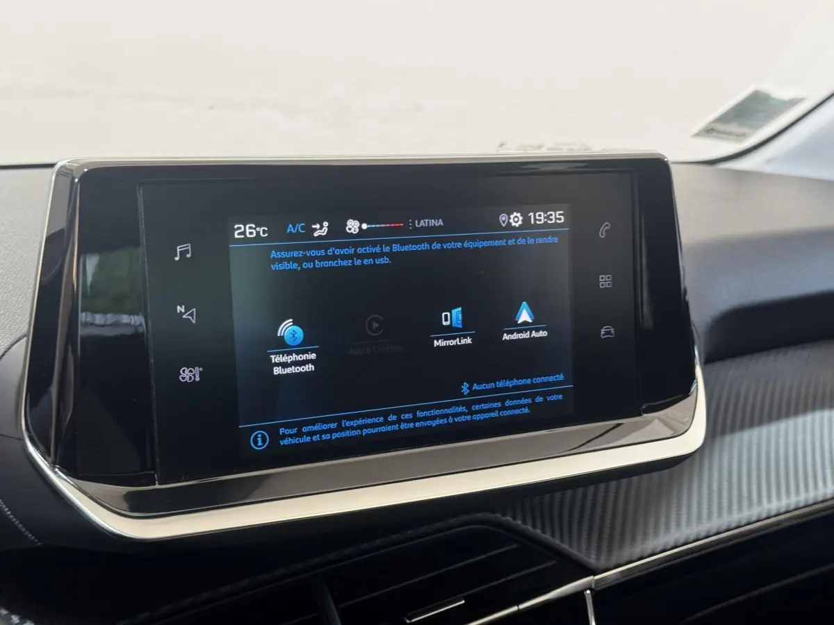 Écran tactile central de la Peugeot 208 jaune, vue rapprochée de la console avec affichage Bluetooth et Android Auto.