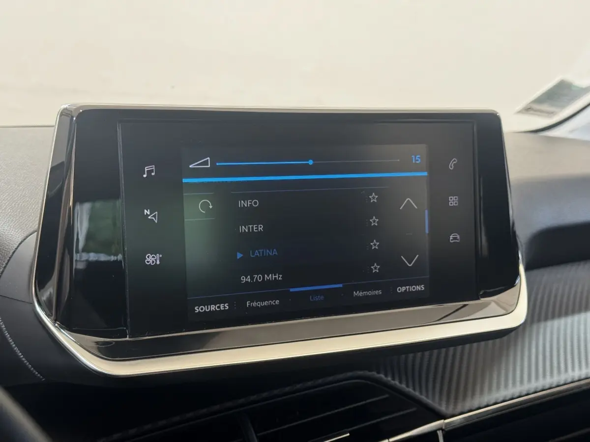 Écran tactile central 7 pouces de la Peugeot 208 jaune, vue rapprochée de l'interface multimédia affichant une radio FM.