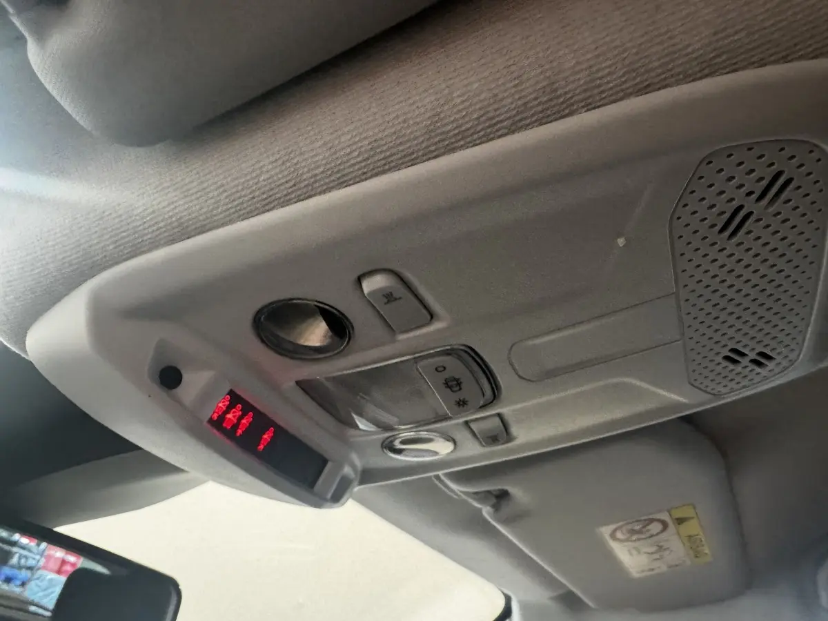 Vue intérieure en gros plan du plafonnier gris avec commandes et affichage lumineux rouge dans une Peugeot 208 jaune.