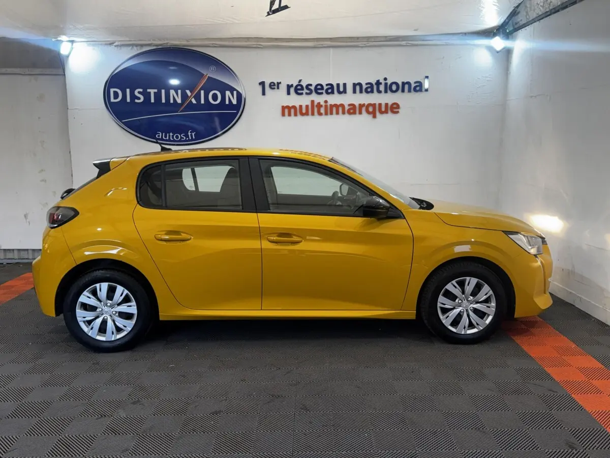 Peugeot 208 jaune vue de profil côté gauche dans un showroom avec sol gris et bandes orange.