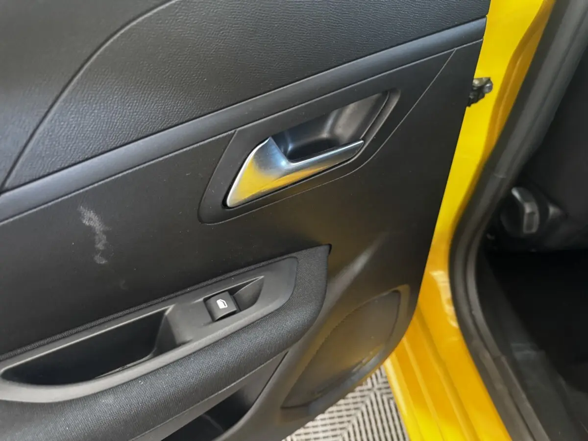 Gros plan sur la porte arrière gauche noire avec poignée argentée et cadre jaune vif de la Peugeot 208 2023.