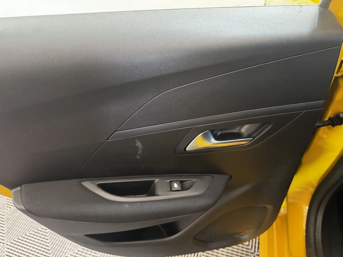 Vue intérieure côté gauche de la porte avant jaune de la Peugeot 208 avec poignée argentée et bouton de verrouillage.