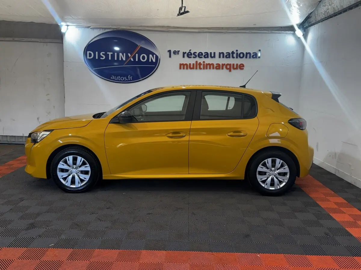 Profil droit d'une Peugeot 208 jaune 2023 garée en intérieur avec jantes alliage et vitres teintées.