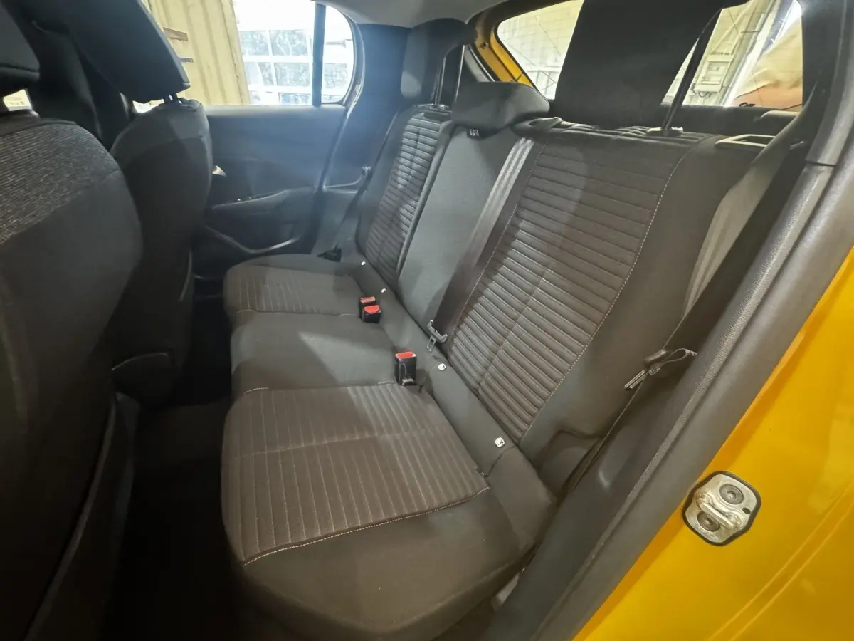 Vue intérieure côté droit des sièges arrière noirs d'une Peugeot 208 jaune 2023, avec ceinture et porte ouvert.