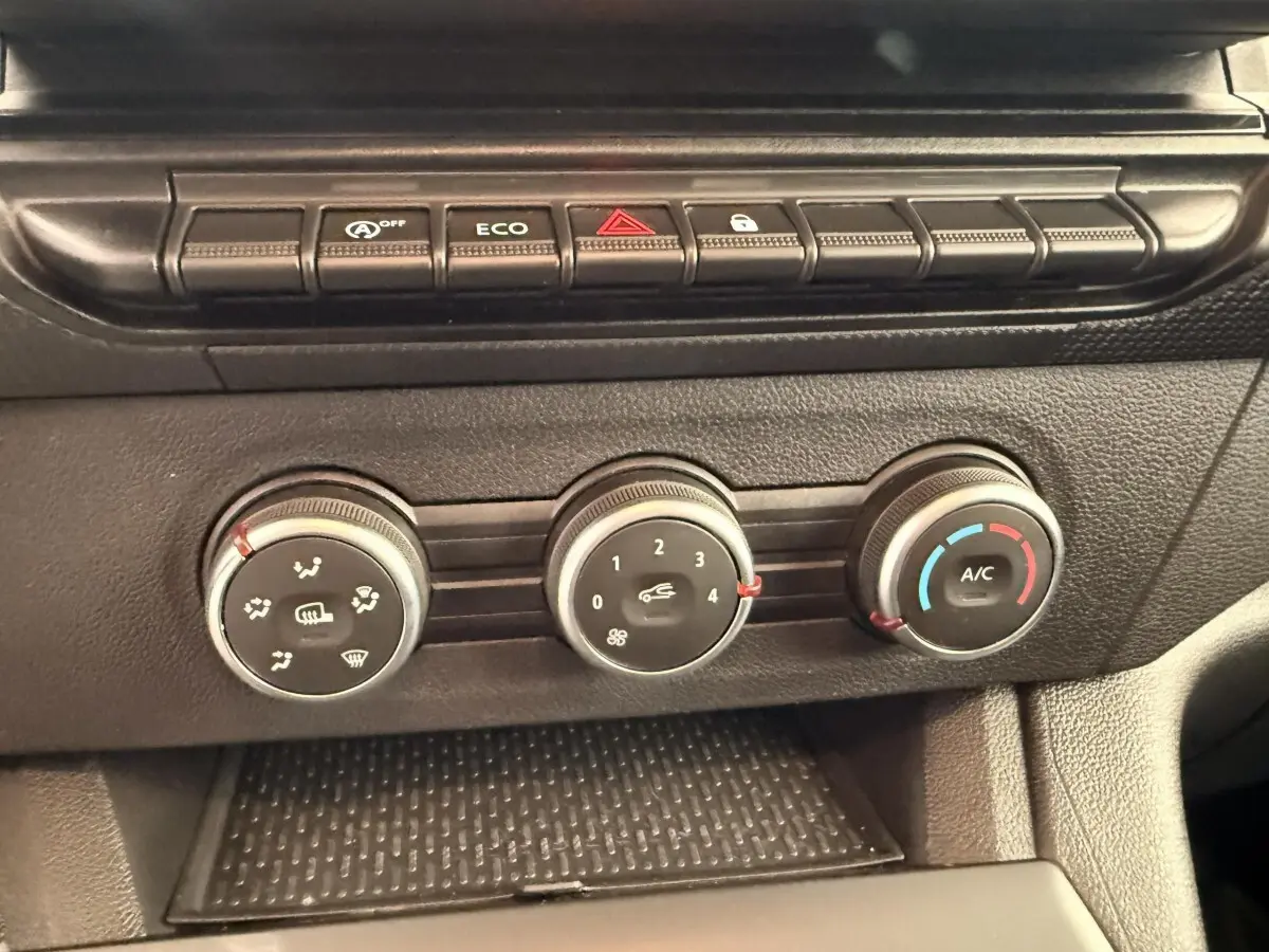 Gros plan sur les commandes de climatisation et boutons de fonction du tableau de bord du Renault Kangoo blanc 2023.
