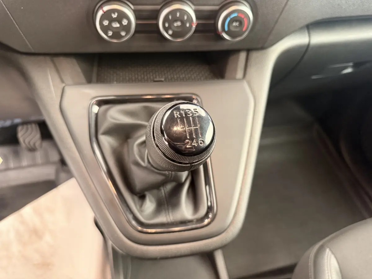 Gros plan sur le levier de vitesses manuel noir du Renault Kangoo GD Confort 2023, avec commandes de climatisation en arrière-plan.