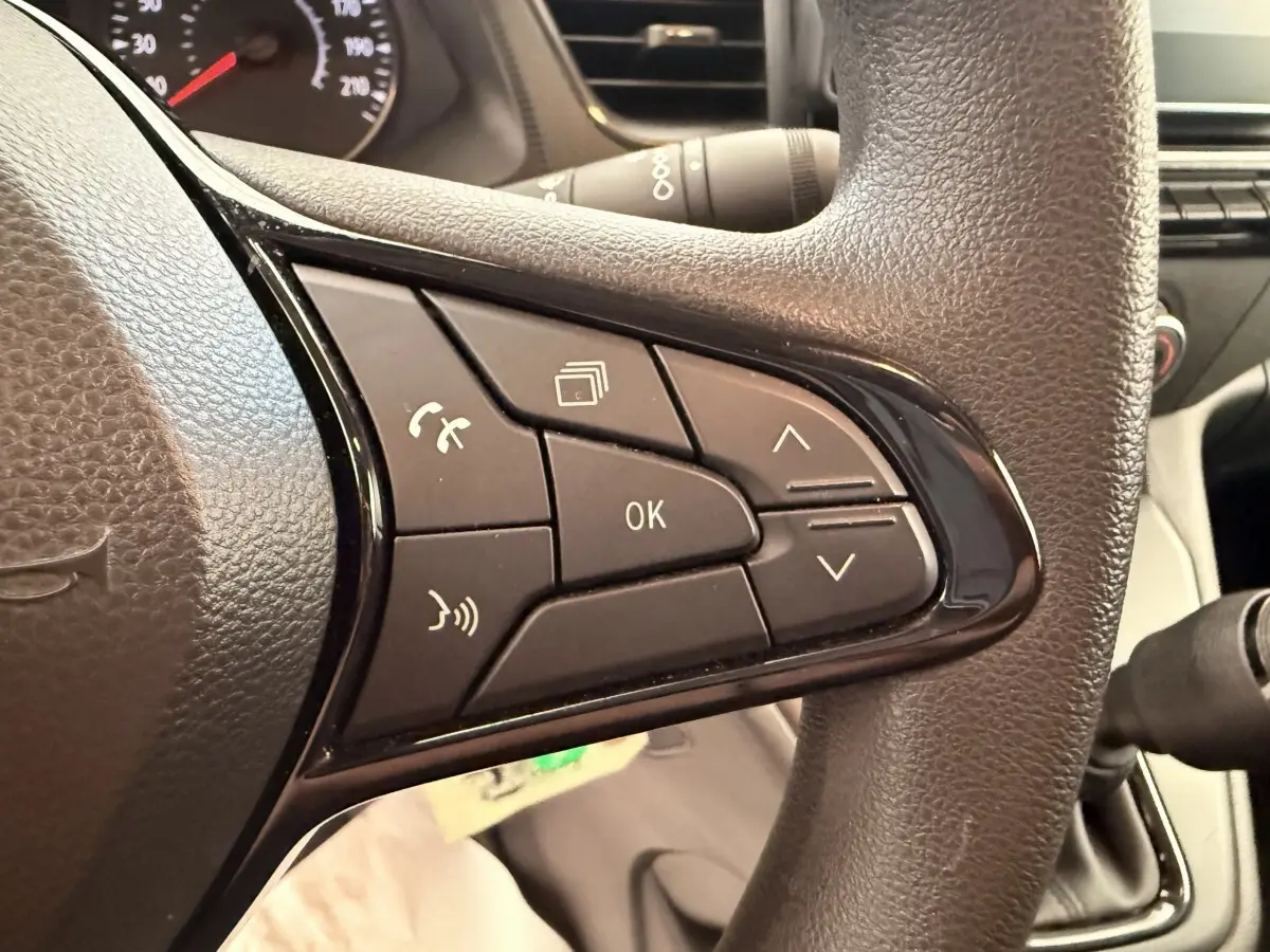 Gros plan sur les commandes multifonctions noires du volant du Renault Kangoo blanc, version GD Confort 2023.