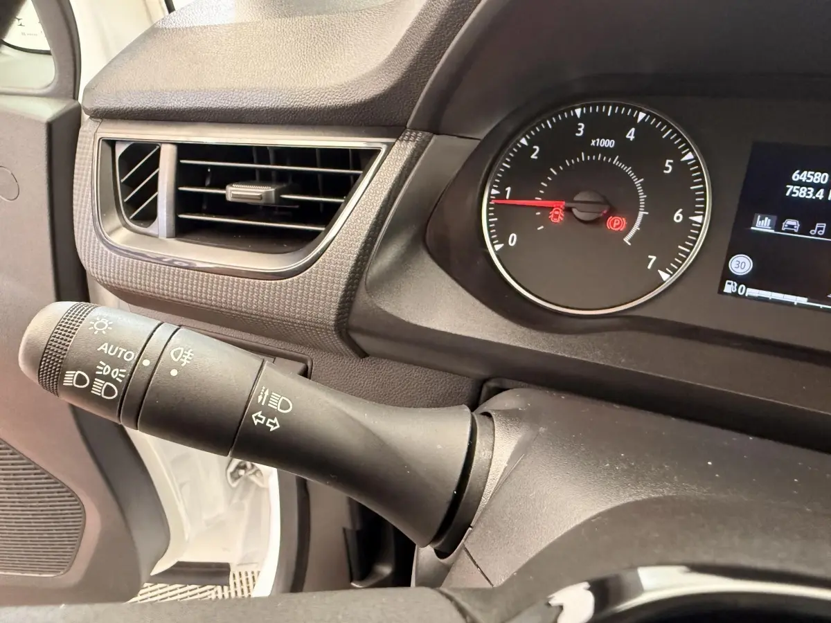 Gros plan sur la manette de phares et clignotants à gauche du tableau de bord noir du Renault Kangoo blanc 2023.