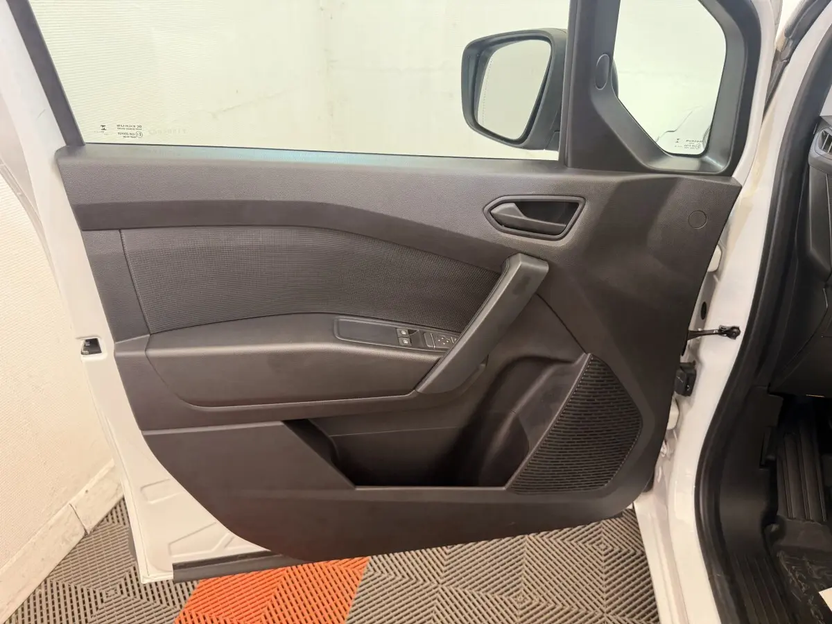 Vue intérieure de la porte avant gauche noire du Renault Kangoo blanc, avec commandes de vitres et rétroviseur visible.
