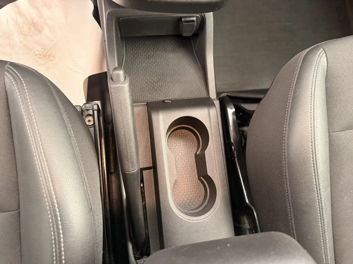 Vue plongeante sur la console centrale noire entre les sièges avant gris du Renault Kangoo blanc 2023.