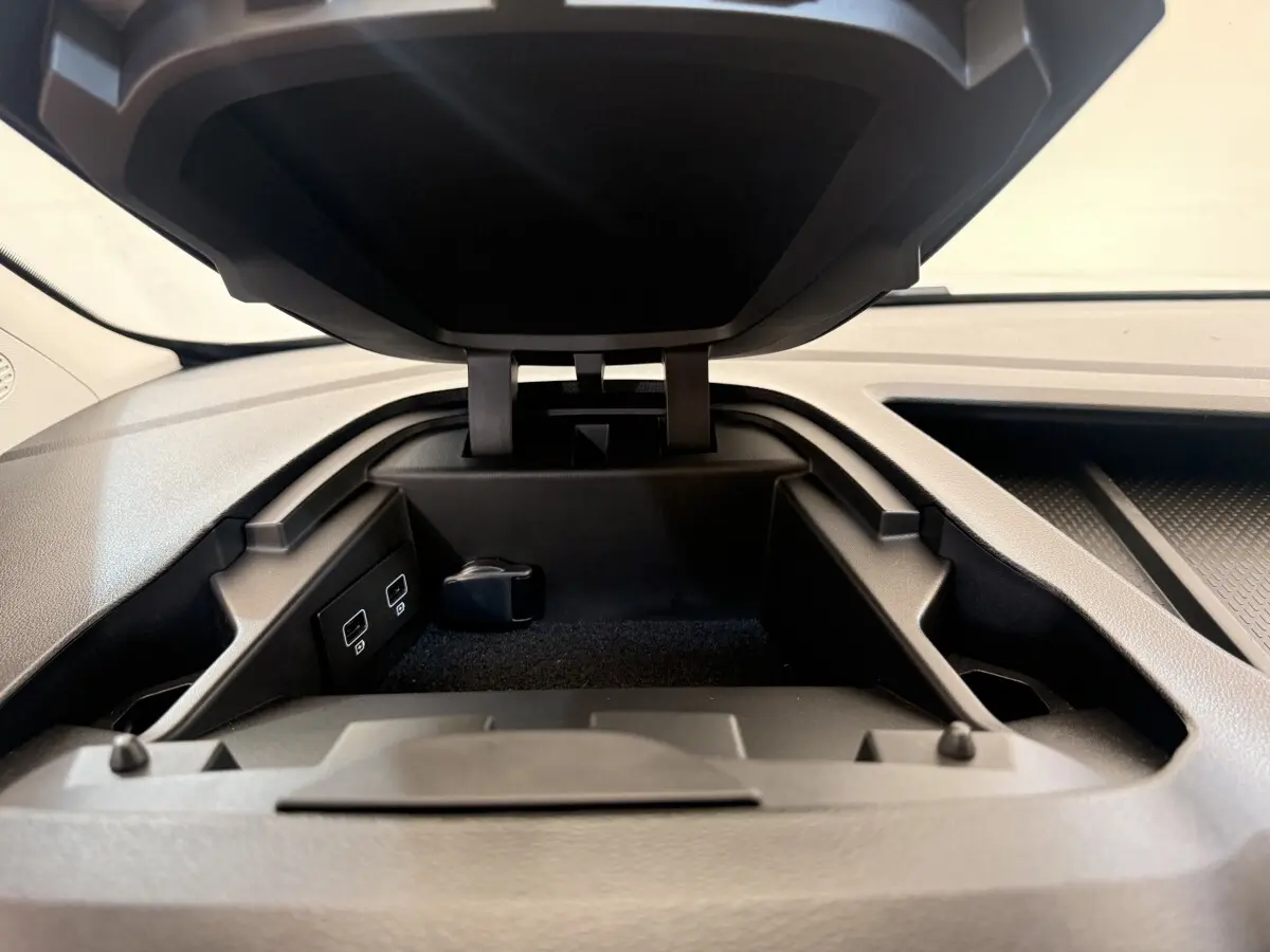 Vue rapprochée du compartiment de rangement ouvert sur le tableau de bord du Renault Kangoo blanc, avec ports USB visibles.