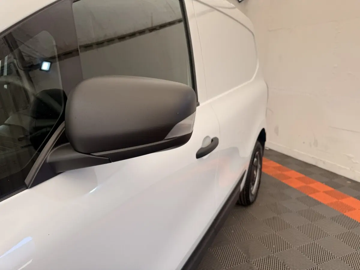 Vue latérale droite rapprochée du Renault Kangoo blanc, mettant en valeur le rétroviseur noir mat et la porte coulissante.