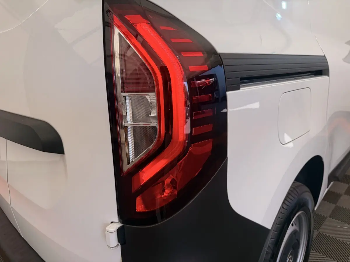 Gros plan sur le feu arrière droit rouge du Renault Kangoo blanc, avec la trappe à carburant visible sur le côté.