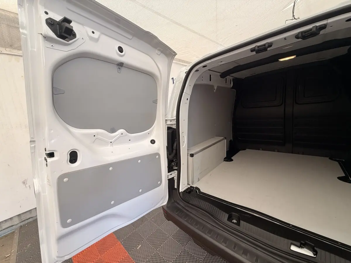 Vue arrière ouverte du Renault Kangoo blanc 2023 montrant l'espace de chargement vide avec cloison intérieure grise.