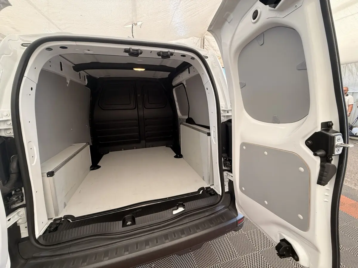 Vue arrière ouverte du Renault Kangoo blanc 2023, montrant l'espace de chargement vide et les parois grises.