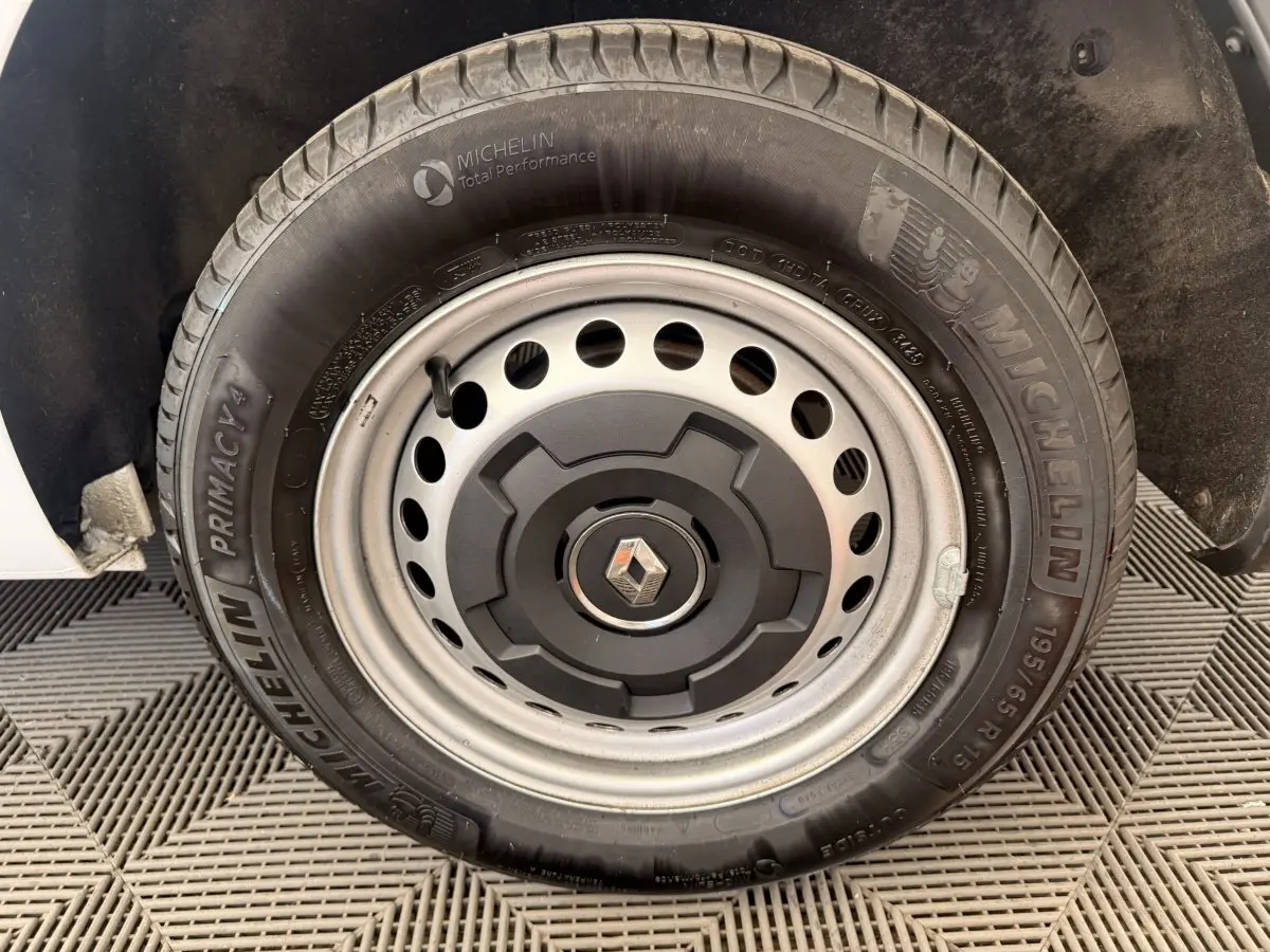 Gros plan sur la roue de secours Michelin avec jante acier et logo Renault au centre du Renault Kangoo blanc.
