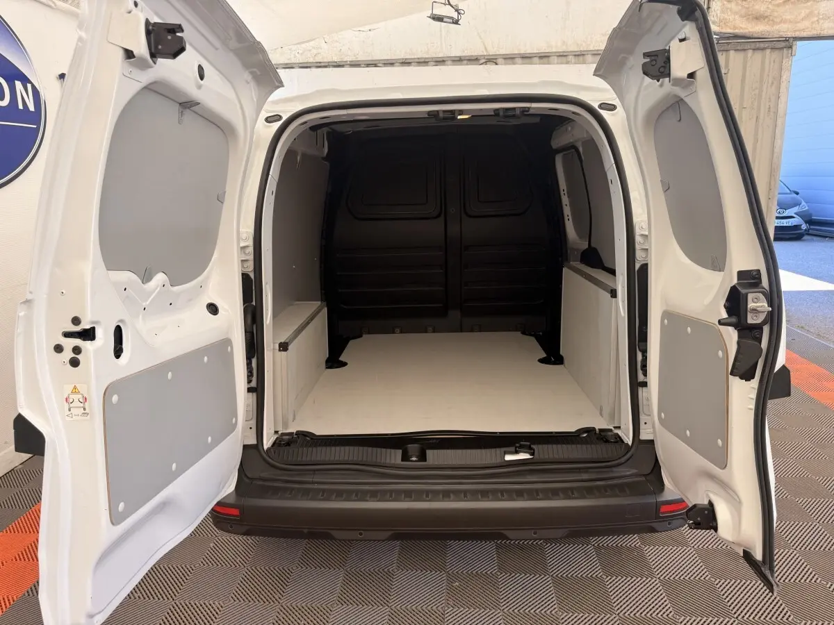 Vue arrière du Renault Kangoo blanc 2023 avec portes ouvertes montrant l'espace de chargement vide et cloison pleine noire.