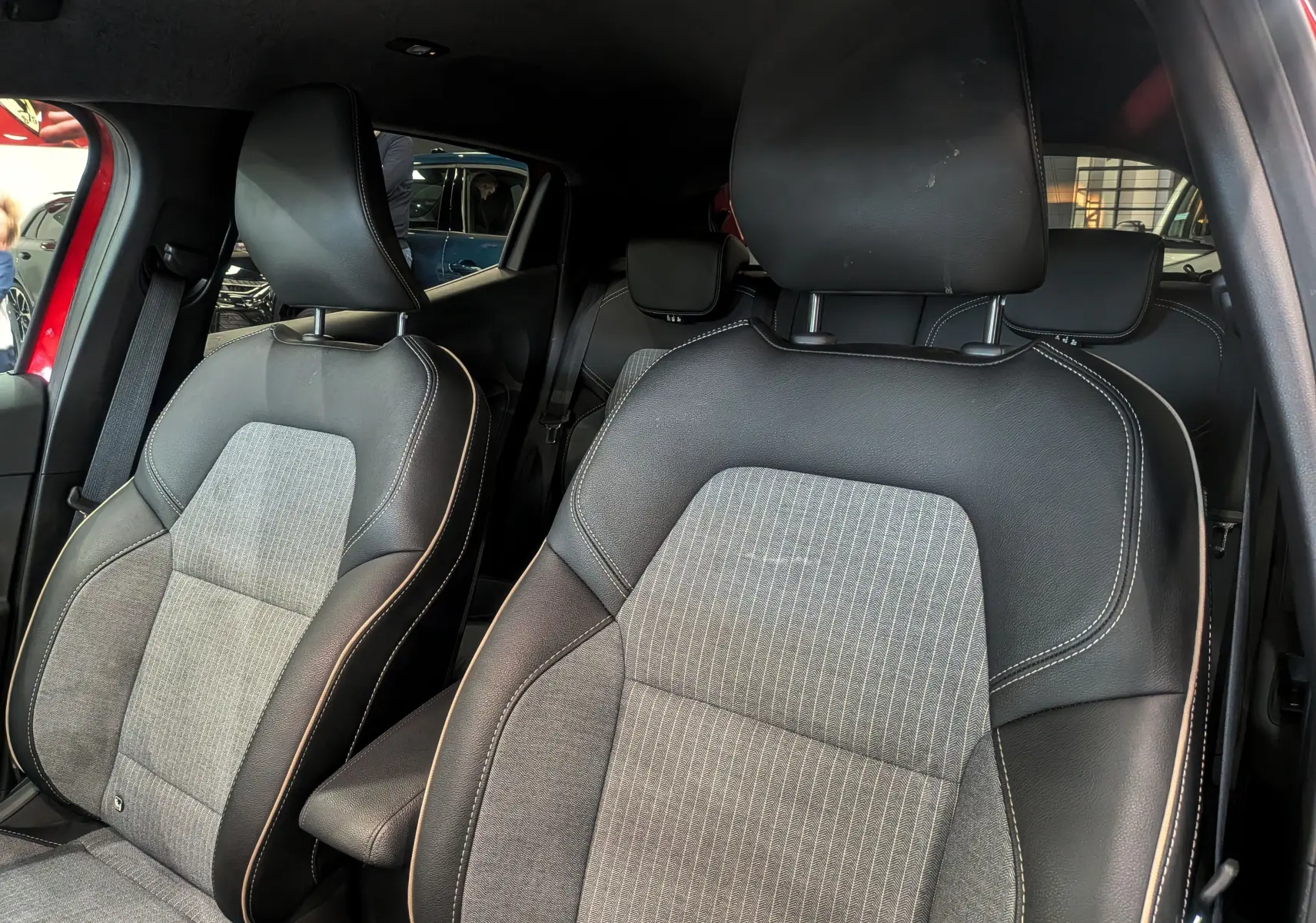 Vue intérieure rapprochée des sièges avant en tissu gris et cuir noir de la Renault Clio V Rouge Flamme 2025.