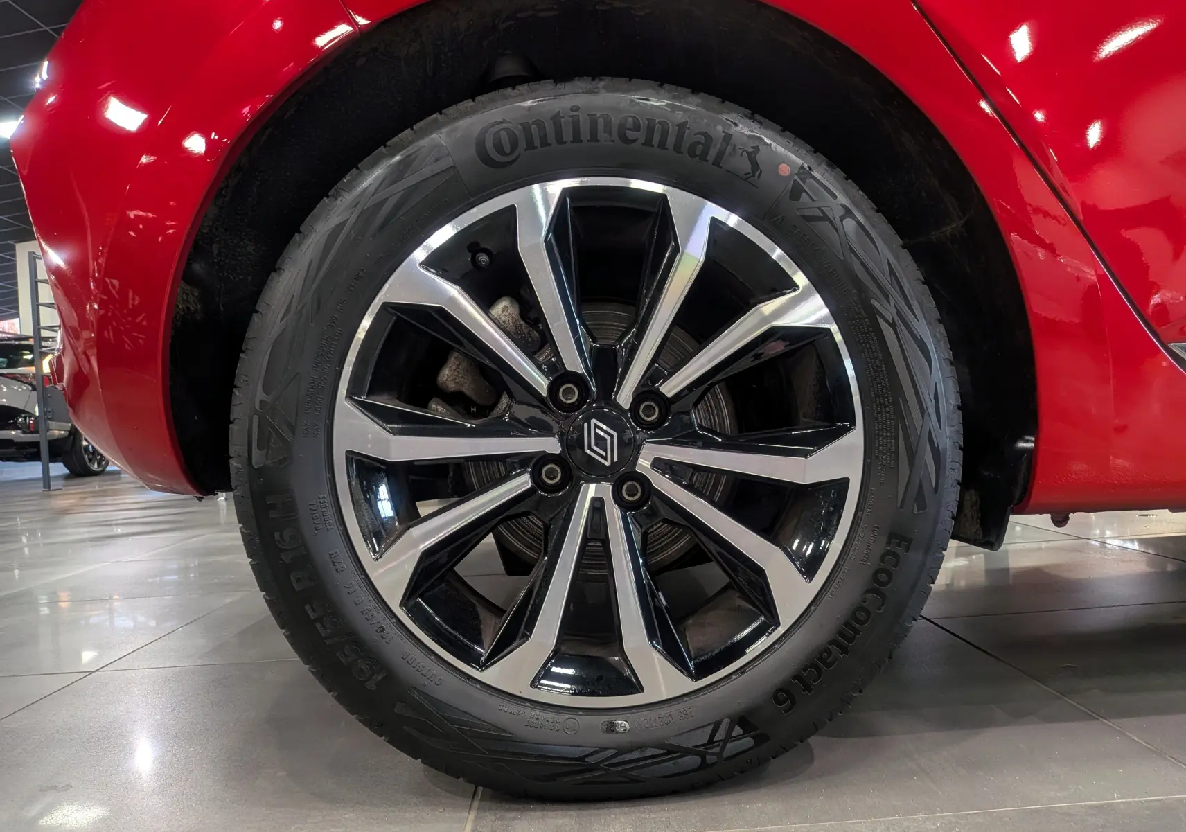 Gros plan sur la roue avant droite d'une Renault Clio V Rouge Flamme avec jante alliage bicolore et pneu Continental.