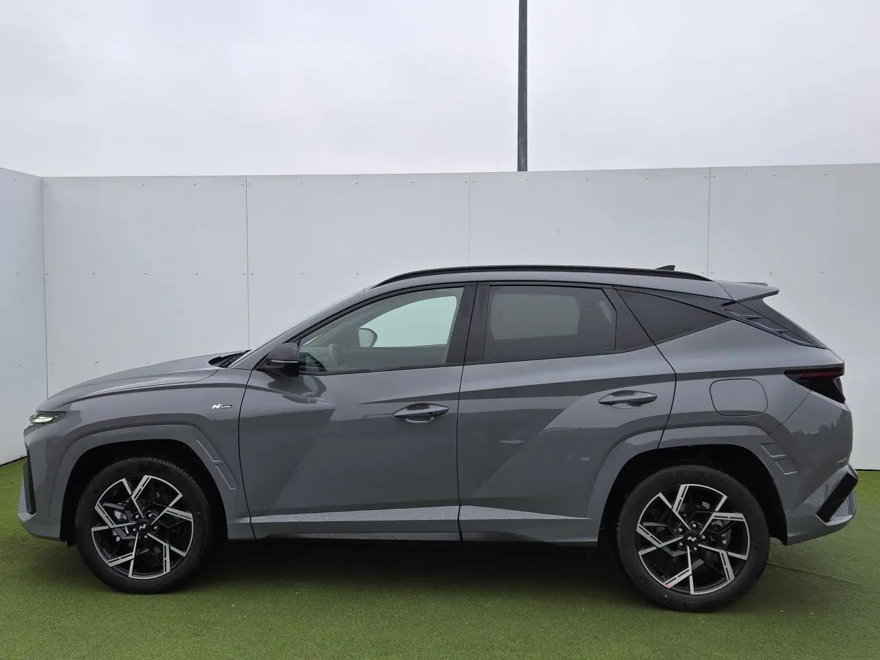 Vue de profil côté gauche du Hyundai Tucson 2025 gris métallisé Shadow Grey avec jantes alliage 19'' N Line distinctives.