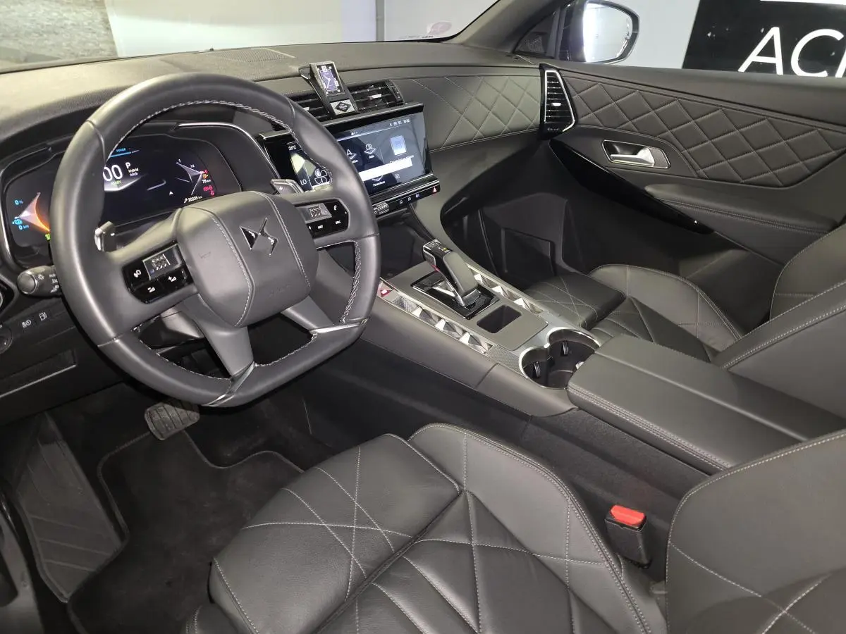 Intérieur noir du DS7 E-Tense 2024 vu côté conducteur, avec volant cuir, tableau de bord numérique et console centrale moderne.