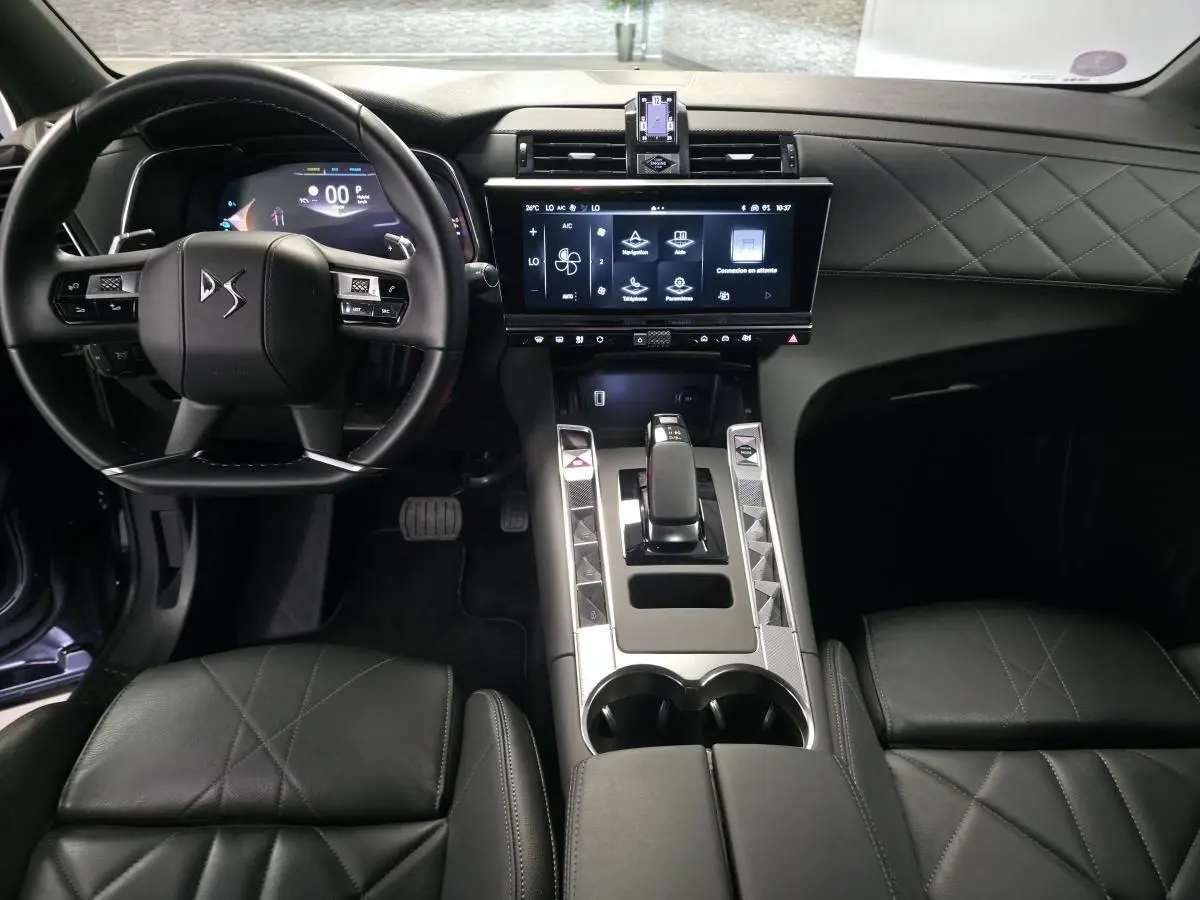 Vue intérieure avant du DS7 Crossback 2024 noir, mettant en valeur le volant cuir, la console centrale moderne et l'écran tactile HD.