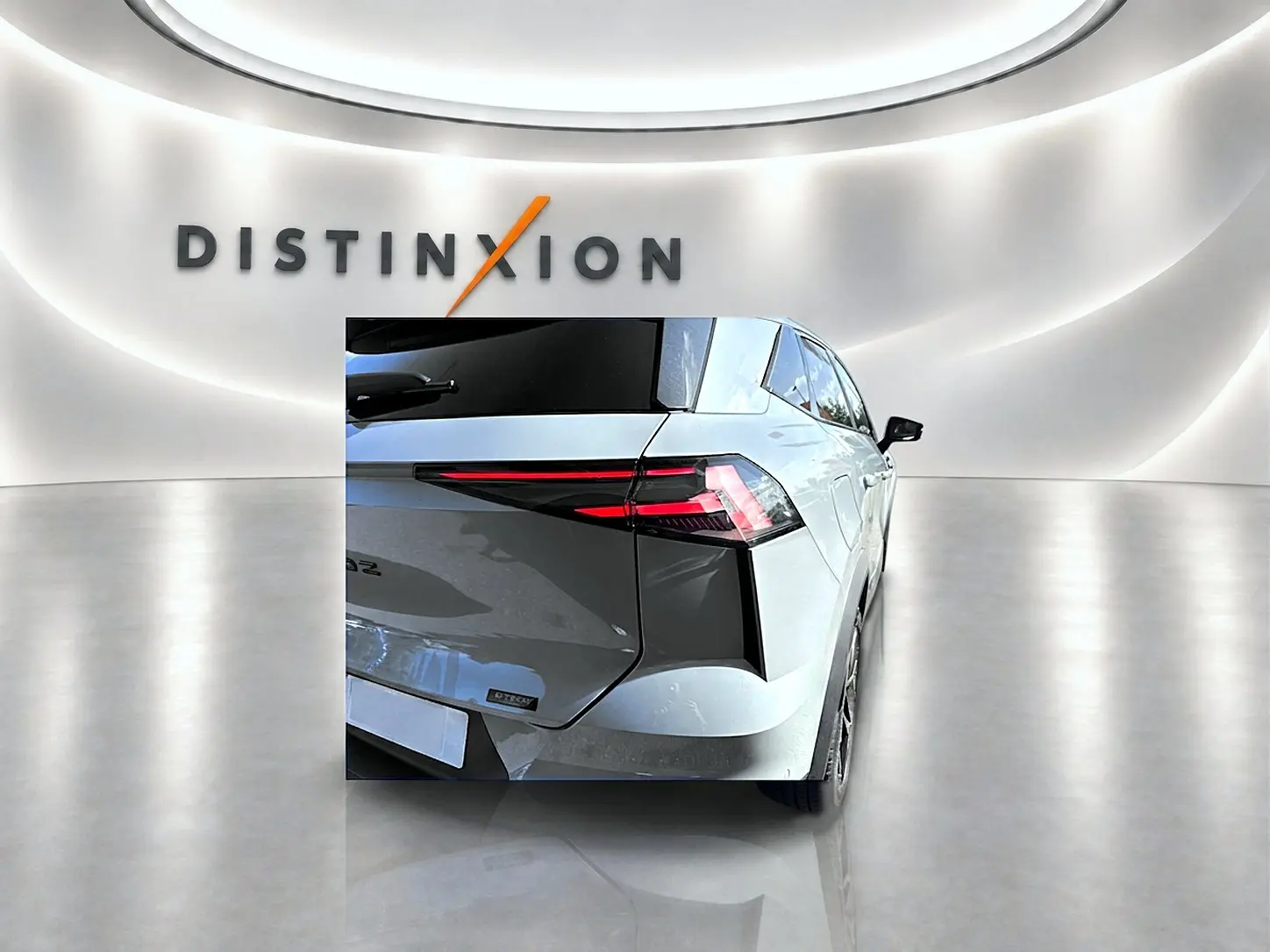 Vue arrière droite du Renault Symbioz gris rafale avec feux arrière LED et becquet distinctif dans un showroom lumineux.