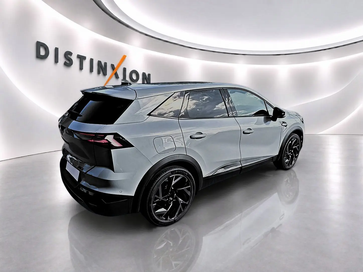 Vue 3/4 arrière droite du Renault Symbioz gris rafale avec jantes noires et vitres surteintées dans un showroom lumineux.