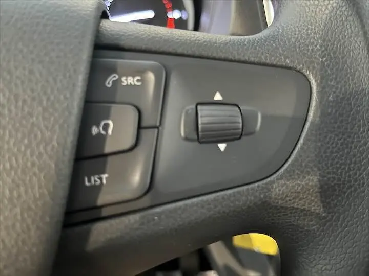 Gros plan sur les commandes du volant du Fiat Scudo cabine approfondie, finition tissu noir, intérieur sombre.