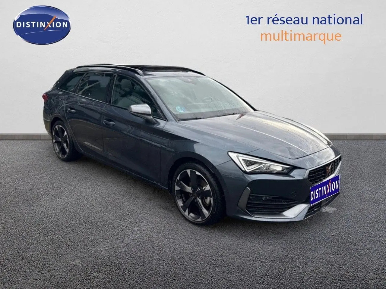CUPRA Leon ST gris magnétique métal en 3/4 avant droit, avec jantes noires bi-ton et phares LED allumés.