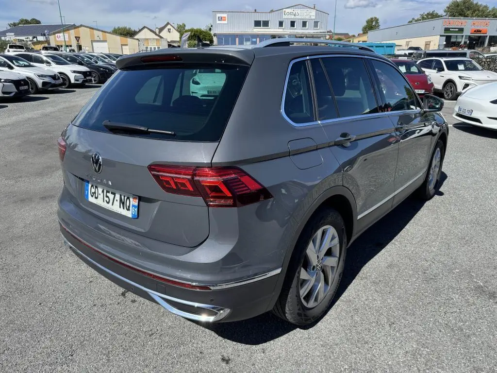 Vue 3/4 arrière droite d'un Volkswagen Tiguan gris avec feux arrière LED et jantes alliage 18 pouces sur parking.