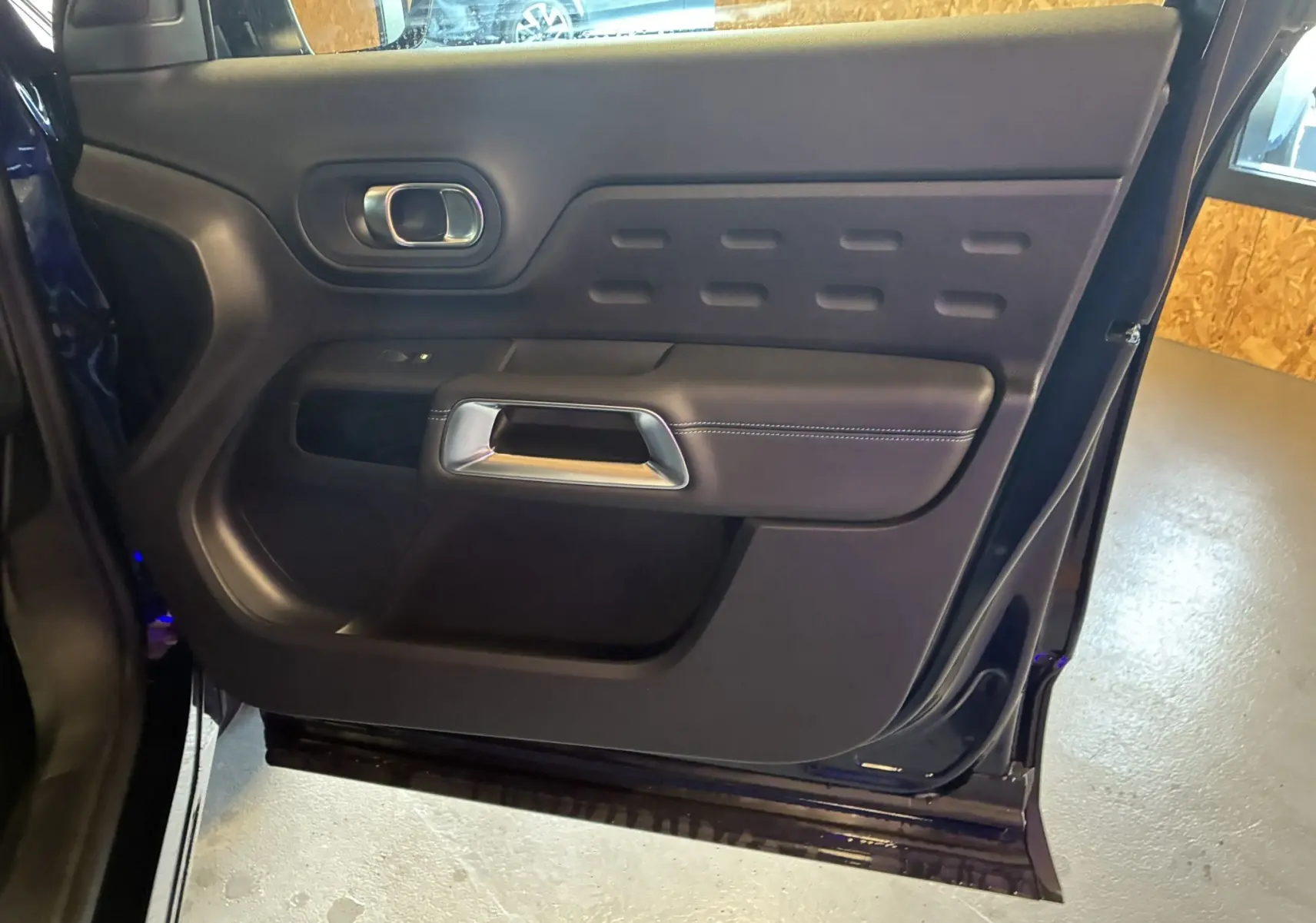 Porte arrière gauche ouverte du Citroën C5 Aircross bleu Eclipse Metal, montrant le panneau intérieur noir avec poignée chromée.