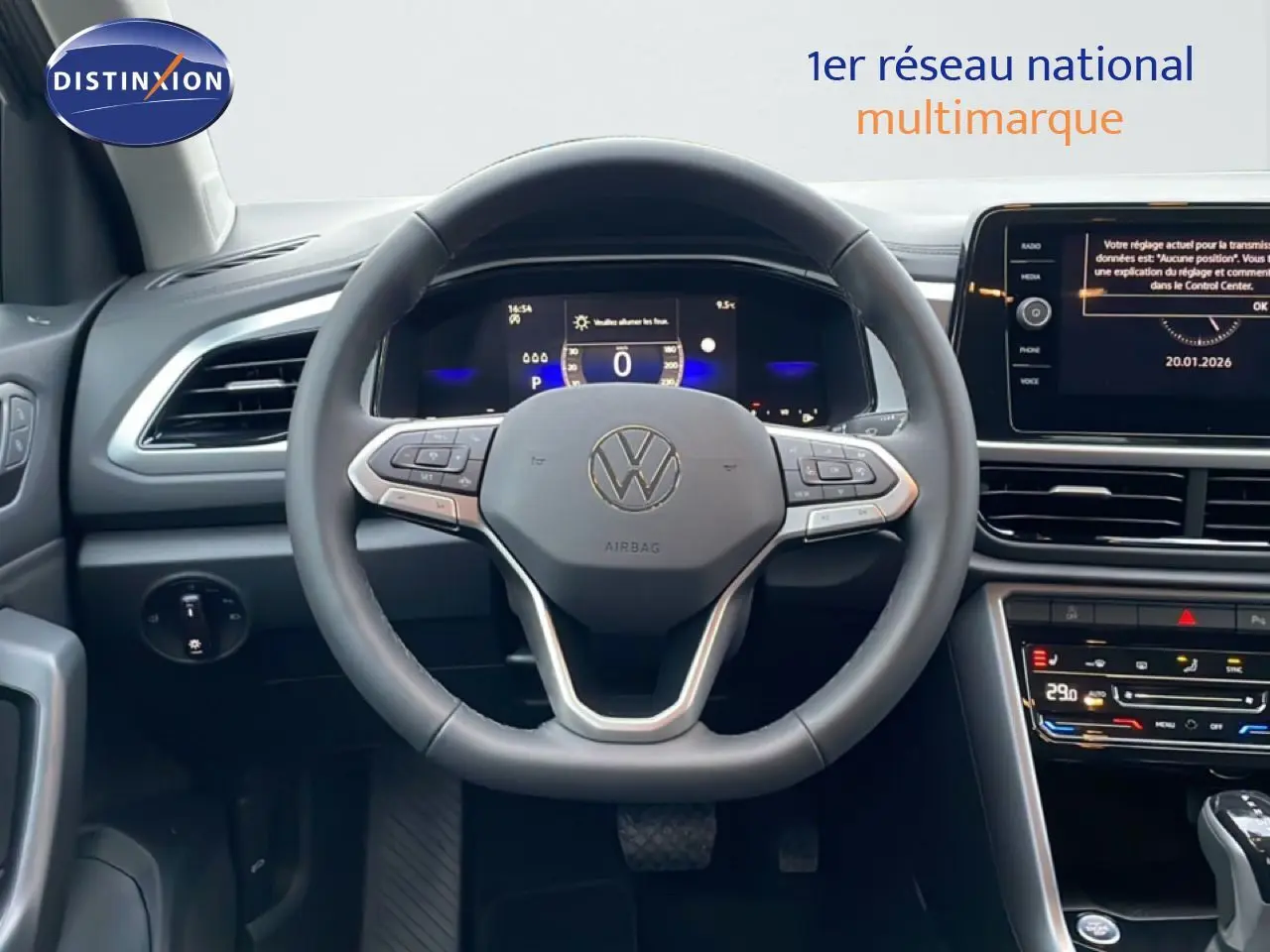 Vue intérieure centrée sur le volant noir du Volkswagen T-Roc avec tableau de bord digital et écran tactile.