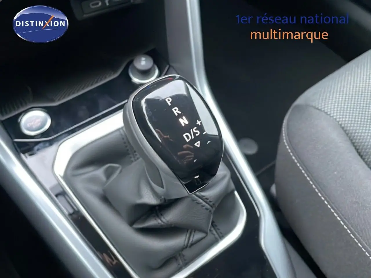 Gros plan sur le levier de vitesses automatique du Volkswagen T-Roc noir Grenadilla, avec sellerie tissu grise visible à droite.