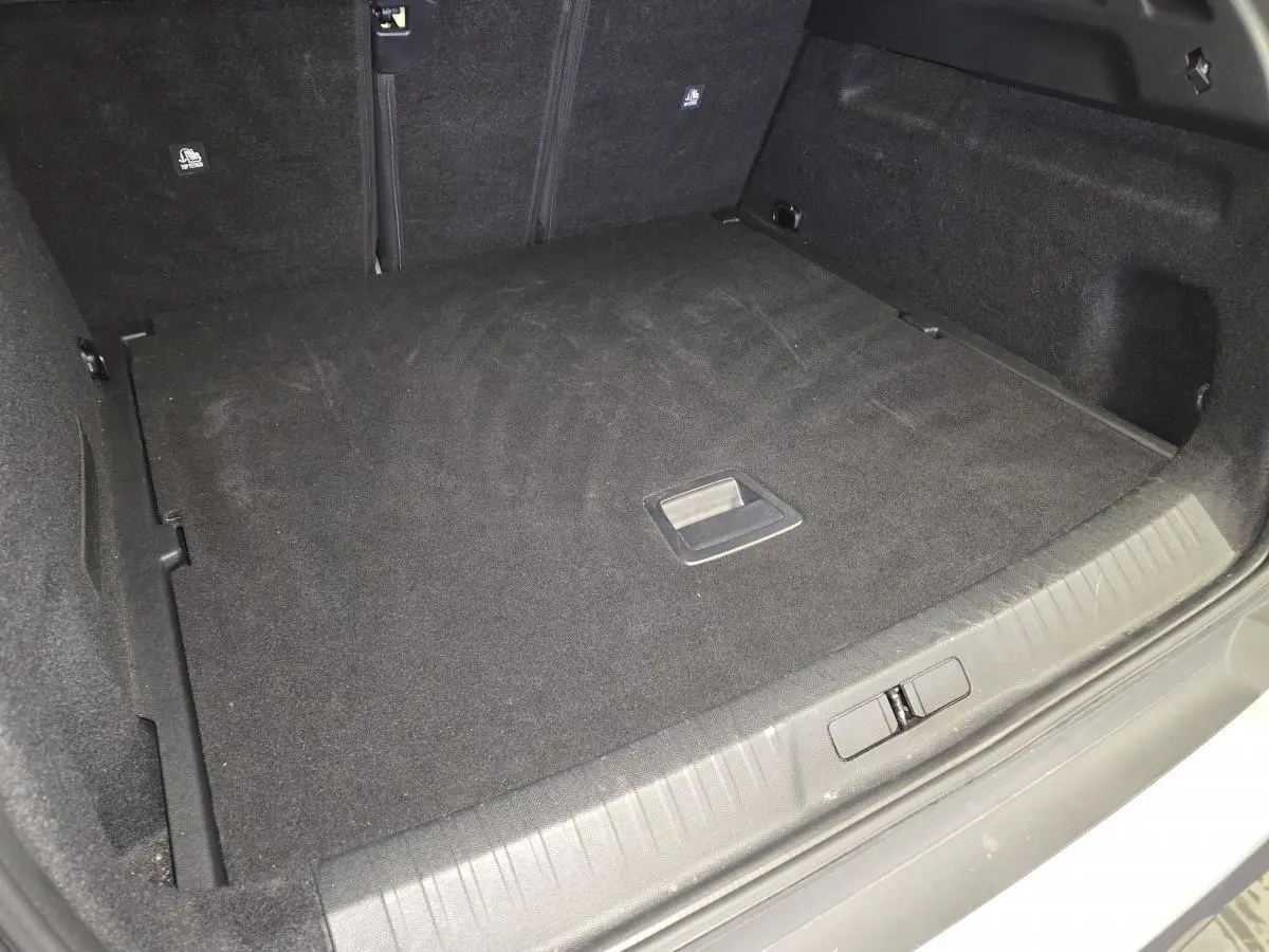 Coffre spacieux et propre du Peugeot 3008 gris, vue depuis l'arrière avec plancher plat et poignée centrale.