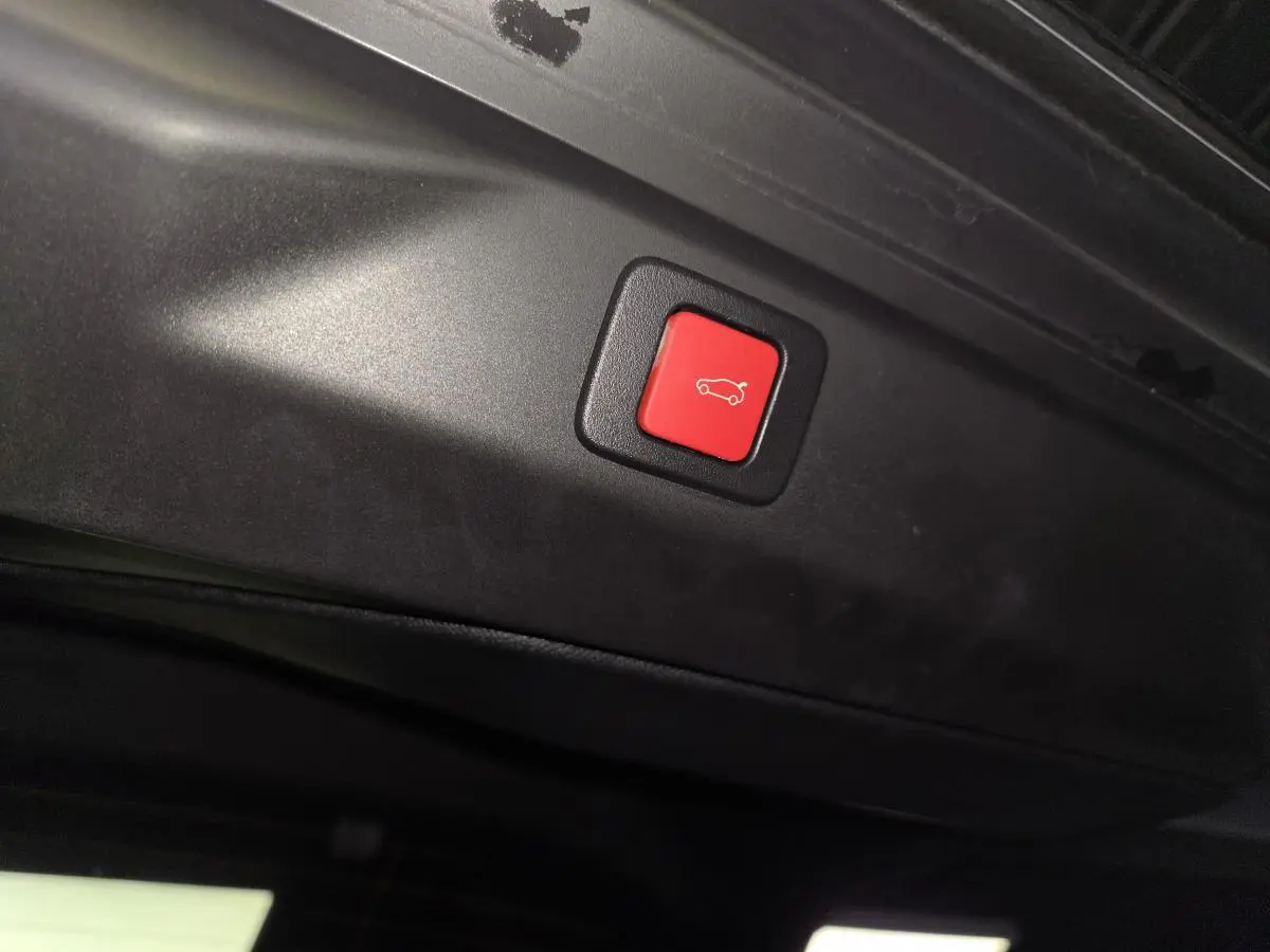 Bouton rouge de fermeture électrique du hayon sur Peugeot 3008 gris, vue intérieure du coffre.