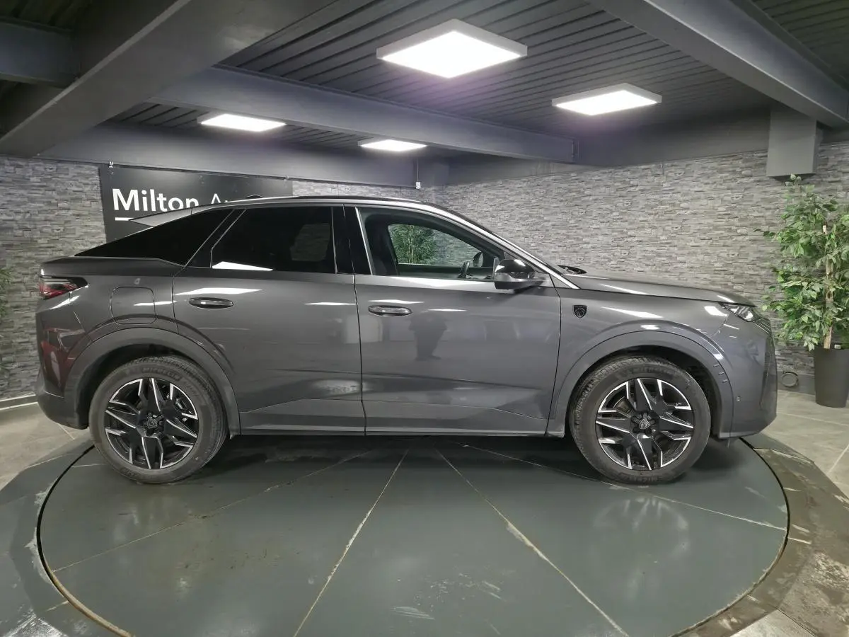 Peugeot 3008 gris en profil droit, jantes alliage noires, toit et vitres arrière teintés, intérieur visible.