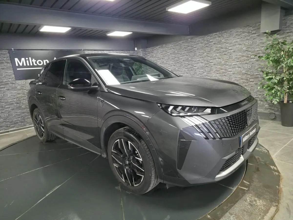 Peugeot 3008 gris métallisé en 3/4 avant droit, avec calandre noire et jantes alliage 19 pouces diamantées.