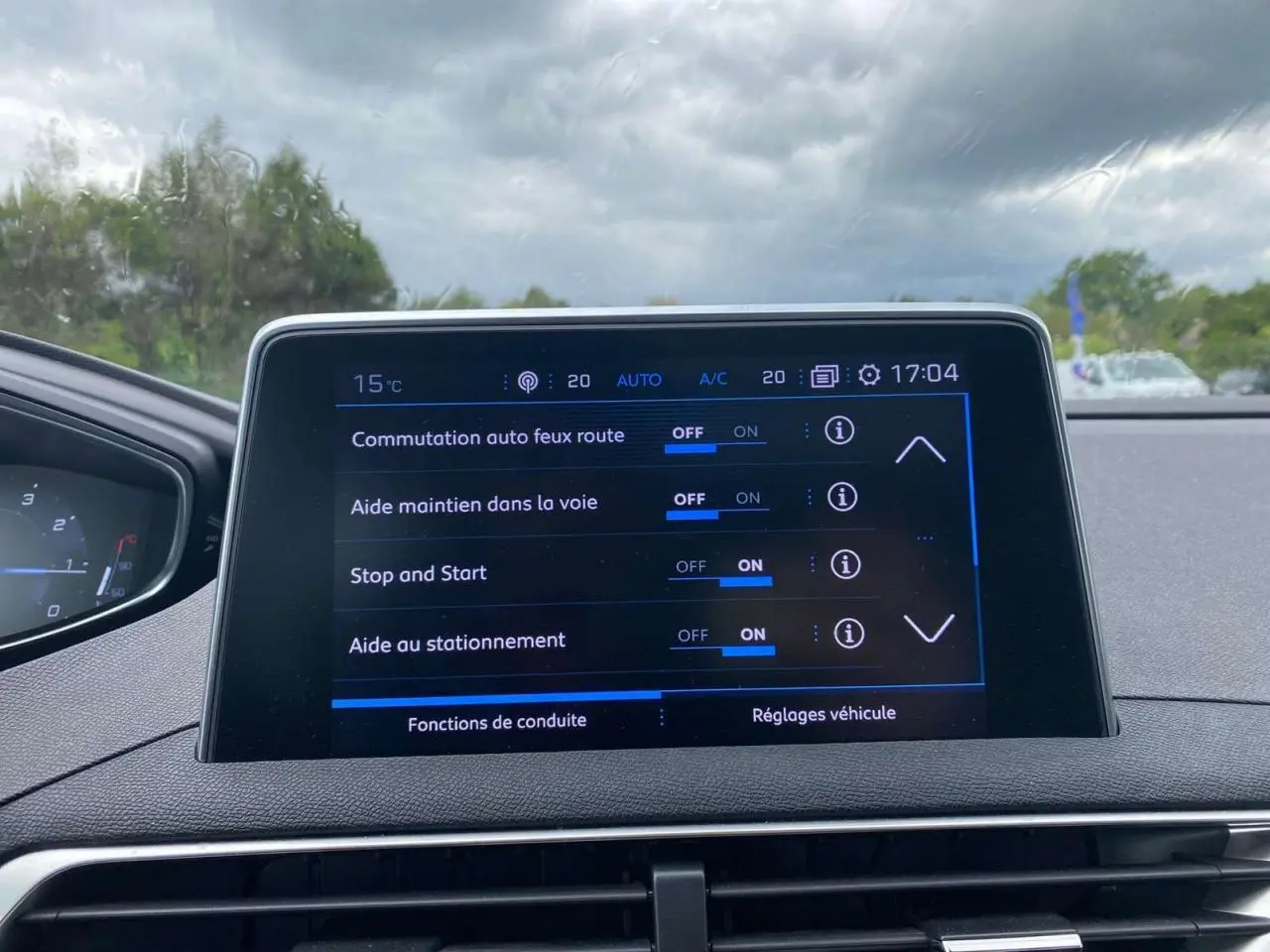 Écran tactile central du Peugeot 3008 blanc 2019 montrant les réglages d’aides à la conduite par temps couvert.