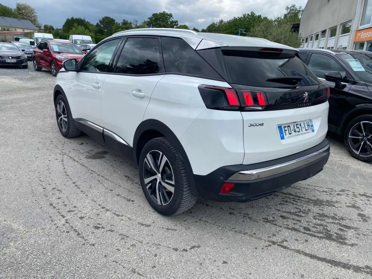 Vue 3/4 arrière gauche d'un Peugeot 3008 blanc nacré avec toit noir, jantes alliage et vitres surteintées.