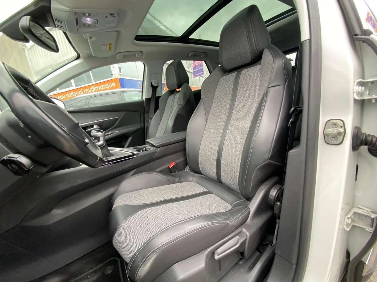 Vue intérieure côté conducteur du Peugeot 3008 blanc 2019, mettant en valeur la sellerie TEP et tissu et le toit ouvrant panoramique.