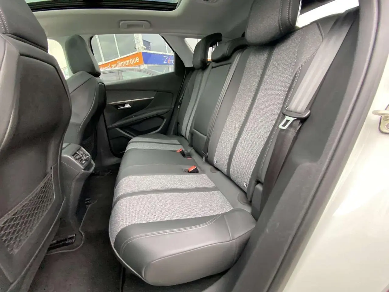 Vue intérieure côté droit des sièges arrière bi-matière tissu gris et cuir noir du Peugeot 3008 blanc avec toit ouvrant panoramique.